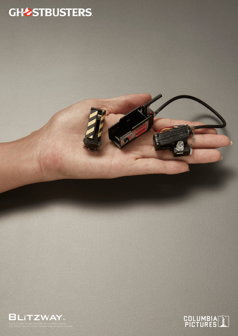 Close-up of the Ghostbusters Ray Stantz 1/6 scale action figure accessories by Blitzway, showing the ghost trap components displayed on a human hand, including the trap cartridge, pedal, and connection cable.