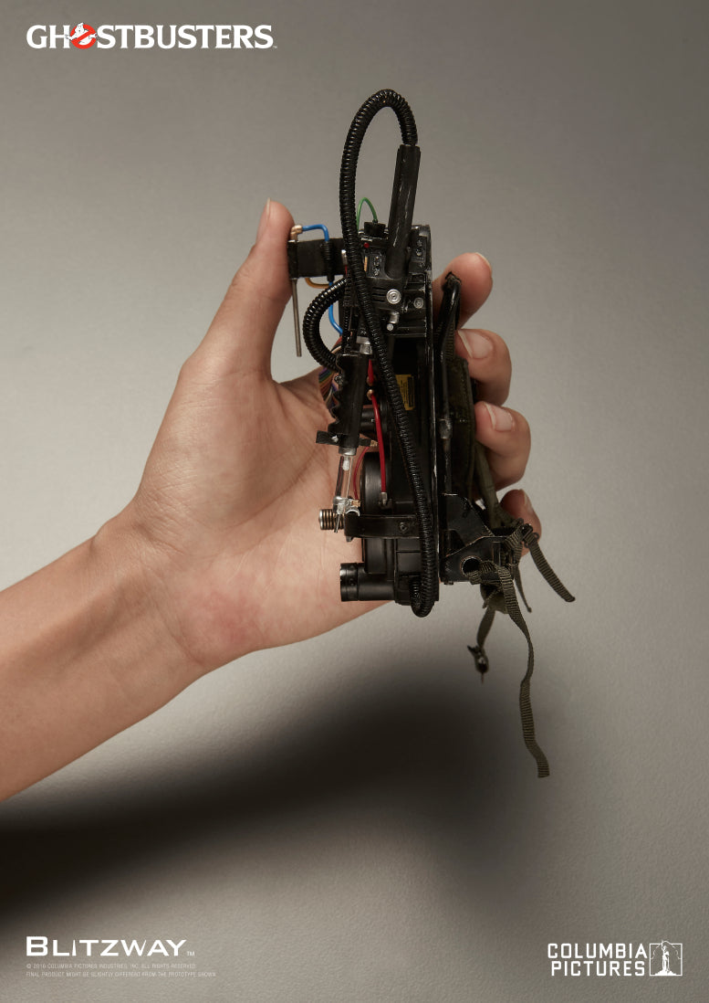 A hand holding the miniature proton pack from Blitzway’s 1/6 scale Ray Stantz Ghostbusters action figure, highlighting the intricate cables, tubes, and detailed components against a neutral background.
